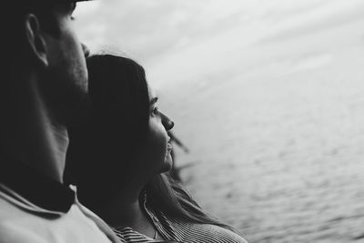 Black and white photo of a young couple in love hugging and looking romantically into the distance.