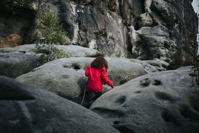 Rear view of woman climbing on rock