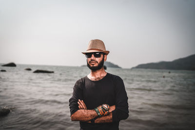 Young man wearing hat standing in sea against sky