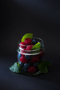 Close-up of strawberries in jar against black background