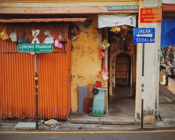 Street name sign against garbage bags on metallic wall