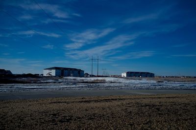 Built structures on field against blue sky during winter