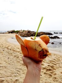 Close-up of hand holding ice cream on beach