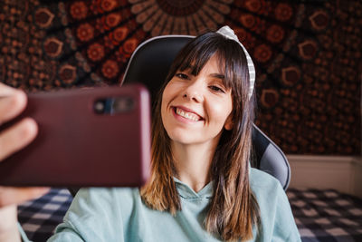 Smiling young woman taking selfie over mobile phone