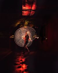 Woman standing by illuminated light trails at night