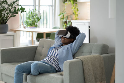 Impressions smiling african american young woman using vr headset immersing herself in metaverse