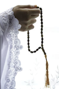 Close-up of hand holding cross against white background