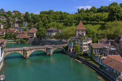 Arch bridge over river amidst buildings in city against sky