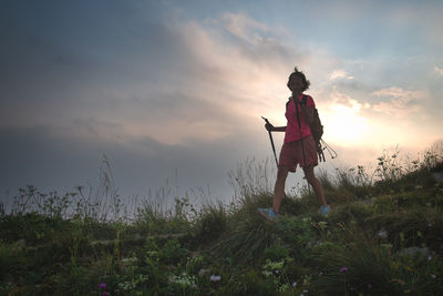 Man standing on field against sky during sunset