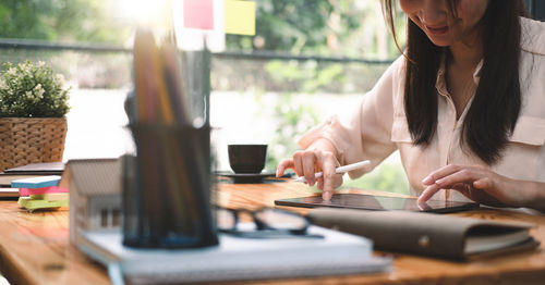 Midsection of woman using digital tablet at office