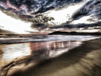 Scenic view of beach against cloudy sky