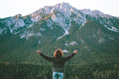 Rear view of woman standing on mountain against sky