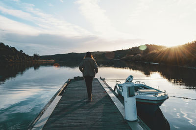 Rear view of woman standing on lake against sky