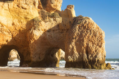 Rock formation on beach against sky