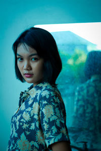 Portrait of young woman looking at camera against the mirror