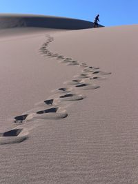 Person walking on sand at beach against clear sky