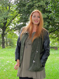 Portrait of young woman standing against tree