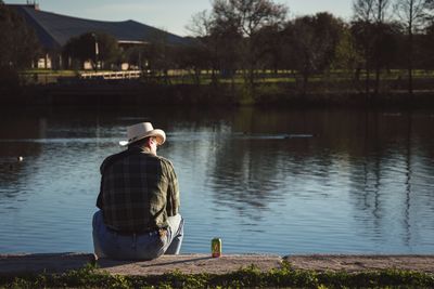 Rear view of man sitting by lake