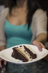 Close-up of woman holding cake slice in plate