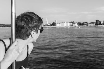 Rear view of man photographing at sea against sky