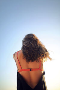 Rear view of woman standing against clear sky