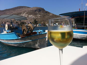 Wine glass on table by swimming pool against sky