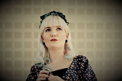 Low angle view of woman holding microphone while standing against wall