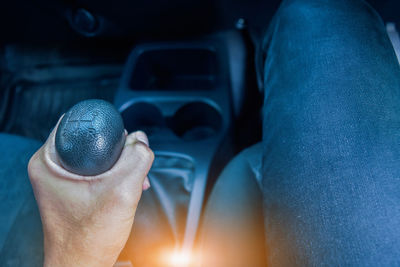 Midsection of man holding gearshift in car