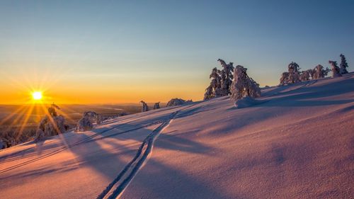 Scenic view of snow covered land against sky during sunset