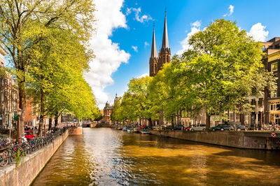 Canal amidst trees and buildings against sky