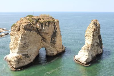 Rock formations in sea against clear sky