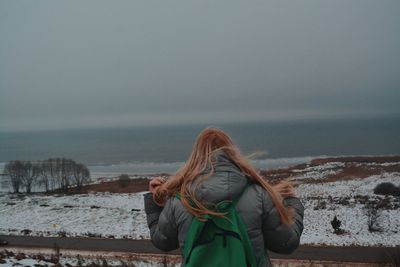 Rear view of woman looking at sea against sky