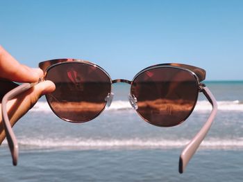 Reflection of man on sunglasses against sea