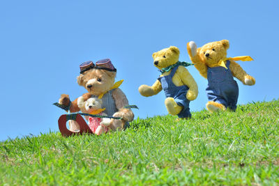 Stuffed toy on field against clear blue sky