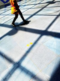 Low section of man walking on street during sunny day