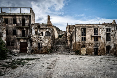 Abandoned buildings against cloudy sky
