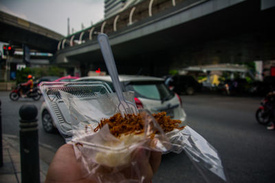 Man holding ice cream cone on street in city