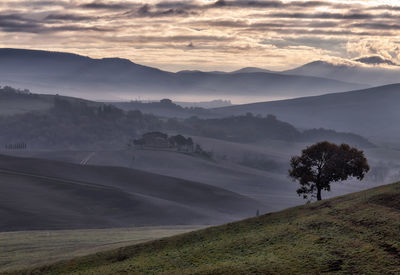 Scenic view val d'orcia landscape against sky during sunset