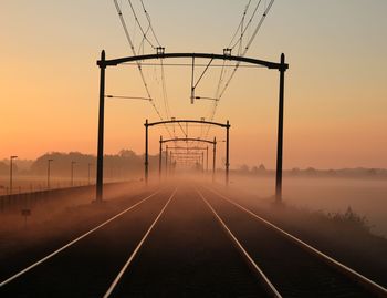 Railroad tracks against sky during sunset