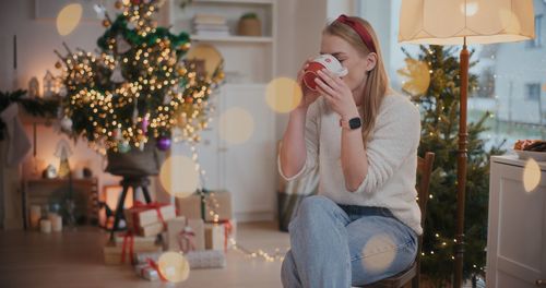 Young woman holding christmas tree at home