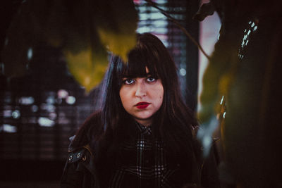 Portrait of young woman standing against tree