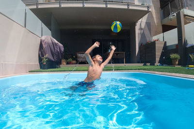 Athletic boy playing with a ball on a swimming pool