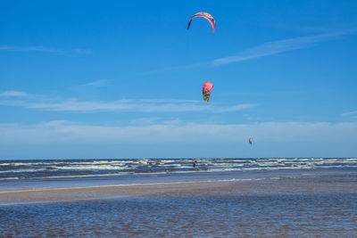 Parachutes over sea against sky