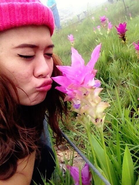 flower, person, fragility, freshness, lifestyles, leisure activity, pink color, girls, innocence, childhood, grass, elementary age, close-up, headshot, focus on foreground, flower head, growth, smiling