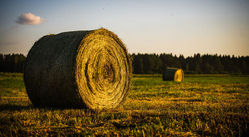 Hay bales on field against sky during sunset