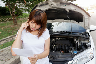 Young woman holding a while standing by car