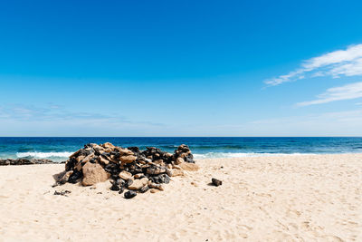 Rocks on beach against blue sky