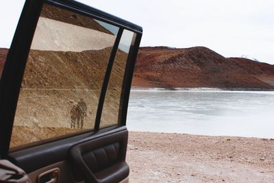 View of lake and hill from open car door