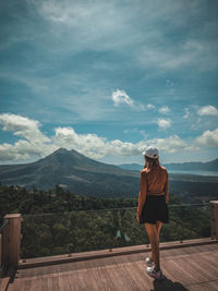 Rear view of man standing on mountain against sky