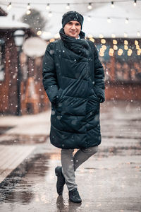 Full length portrait of young woman standing in snow